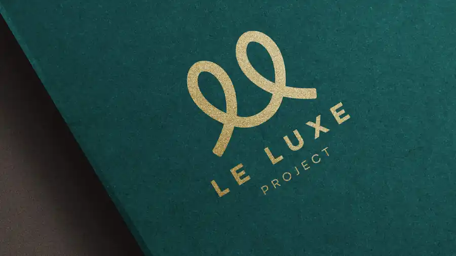 Le Luxe Project logo in gold foil on teal paper